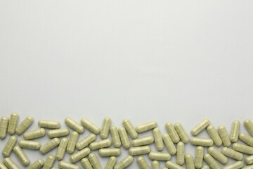 Vitamin capsules on light grey background, top view and space for text. Health supplement