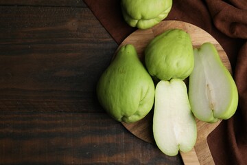 Cut and whole chayote on wooden table, flat lay. Space for text