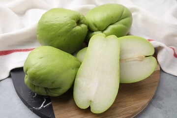 Cut and whole chayote on gray table, closeup