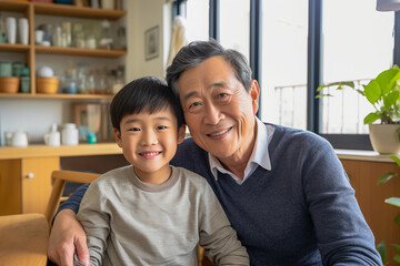 Cheerful Asian grandfather with young grandson smiling together at home.