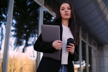 A businesswoman with a laptop works outdoors, embodying the roles of an office worker, social media manager, and freelancer, enjoying outdoor work.