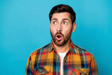 Portrait of impressed guy with stubble wear checkered shirt look at crazy proposition empty space isolated on blue color background
