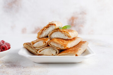 Crepes with cottage cheese, strawberry and mint. Thin pancakes with fillings