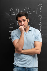 An irritated and shocked guy stands in front of a board covered with various chemical formulas. Technical Education Complexity Concept