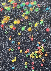 Fruit rings cereal spilled on asphalt with some smashed into colorful dust