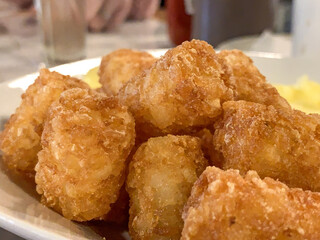 Golden, fried, potato nuggets stacked on plate