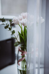 Pink tulips are in a vase in the room.
