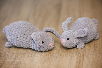 Knitted cute toy rabbits eat carrots. Close-up