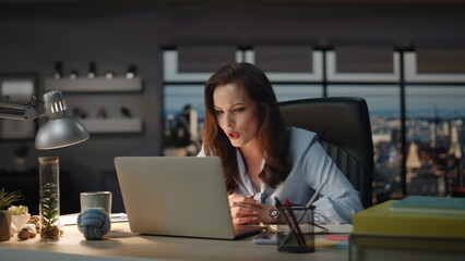Serious businesswoman talking online meeting panoramic dark office. Woman call