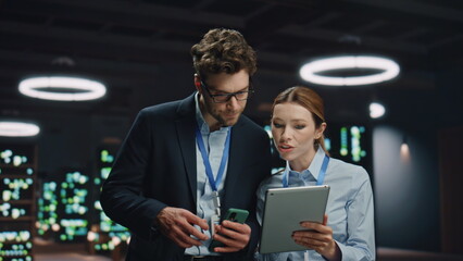 IT engineers working tablet in night data center closeup. Colleagues discussing