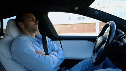 Male businessperson experience to ride an autonomous self driving electric car at urban road. Confident businessman resting during riding on electrical auto with autopilot at city. Slow motion - 759085708