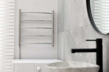 Modern heated towel rail on wall in bathroom