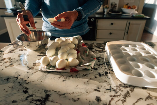 An adult male making deviled eggs. 