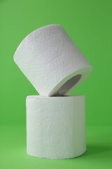 Soft toilet paper rolls on green background, closeup