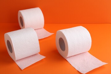 Soft toilet paper rolls on orange background