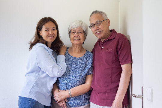 adult daughter with senior asian parents, portrait looking at camera