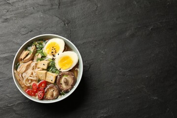Noodle soup. Bowl of delicious ramen on black table, top view. Space for text