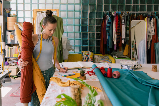 seamstress with a roll of fabric in her hands in the workshop