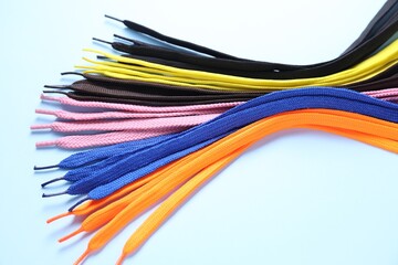 Many colorful shoe laces on light blue background, closeup