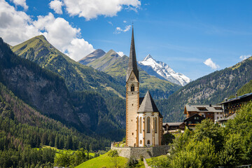 Fototapeta na wymiar Heiligenblut, Carinthia, Austria, A scenic landscape photo of the Austrian municipality of Heiligenblut with St. Vincent Church in front of the Hohe Tauern mountain ridge