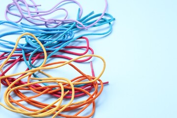 Many colorful shoe laces on light blue background, closeup. Space for text