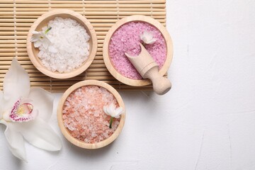 Different types of sea salt and flowers on light table, flat lay. Spa products