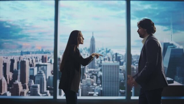 Successful business people in the office. Man and woman ceo hedge fund top manager meeting bumping fists happily in front of window with morning city view.