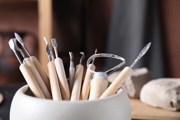 Set of different clay crafting tools on table in workshop, closeup