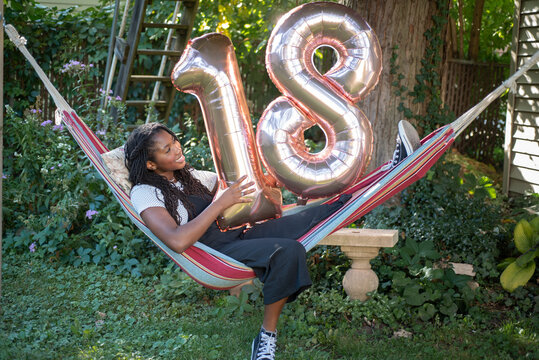 Teen with 18th birthday balloons - Powered by Adobe