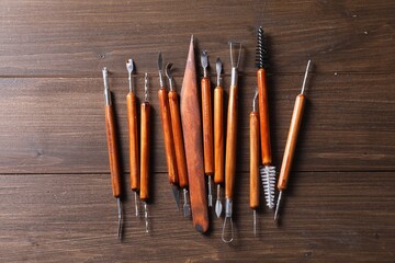 Set of different clay crafting tools on wooden table, flat lay