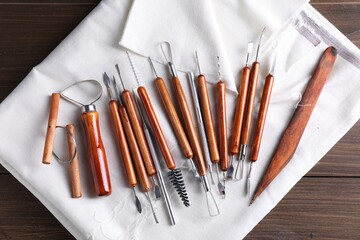 Set of different clay crafting tools on wooden table, top view