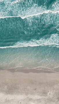 Vertical video of Drone aerial view of paradise beach. Turquoise sea water and clear sand at sunset.