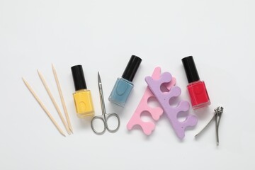 Nail polishes and set of pedicure tools on white background, flat lay