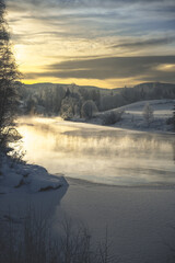 Scenic morning landscape with snowy river, fog, and trees