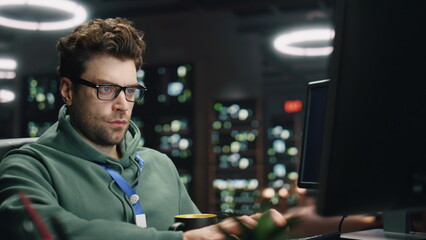 Focused man coding computer keyboard night datacenter closeup. Programer working