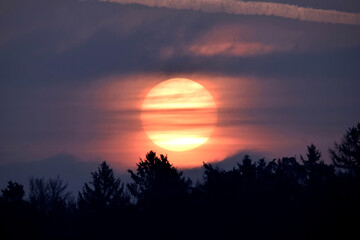 Roter Vollmond durchzogen von leichten Wolkenstreifen 