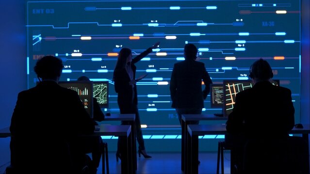 Technical support team in control room. Man and woman specialists discussing work, digital screen shows infrastructure monitoring infographic network data. - Powered by Adobe