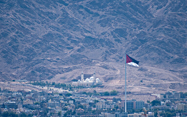 One of the biggest Jordanian mosque  - Al-Sharif Al-Hussein Bin Ali and highest National flag of Arabian Revolt, attractions are located above marine port of Aqaba city, Jordan - 759099748