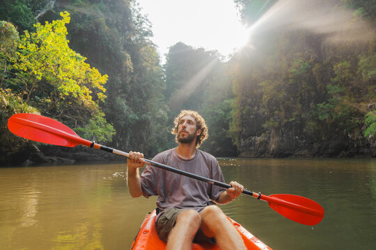 Man kayaking among islands covered in jungles at sunset 
