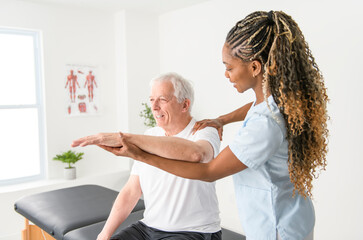 Black physiotherapist helping senior man with in clinic. Elderly man undergoing physiotherapy treatment for injury - 759103164