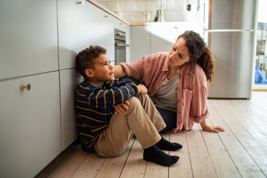 Mother and son having a serious conversation on the kitchen floor