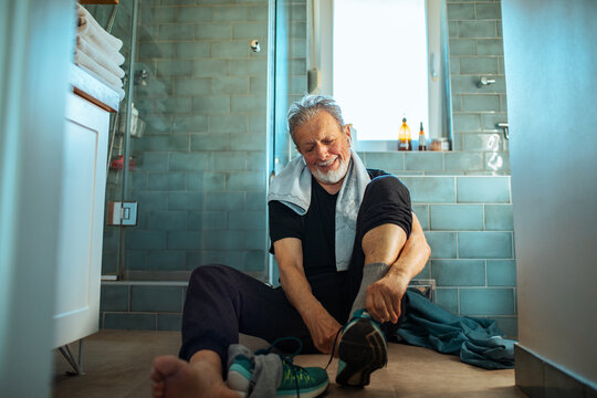 Elderly man tying shoe laces at home before exercise