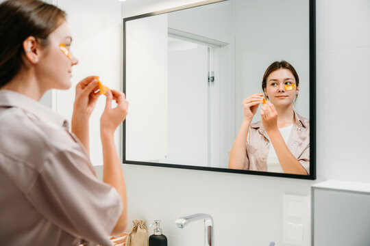 A woman applies eye patches