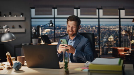 Laughing boss reading smartphone night office closeup. Joyful man looking phone