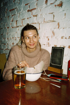 Smiling woman with glass of beer smiling in cafe. Film picture UGC