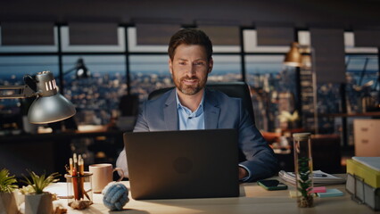 Happy manager reading computer in dark office closeup. Smiling man overworking