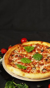 Pizza margherita on a black table, top view. Ingredients for making pizza. Traditional, classic, delicious Italian food on a dark background. Pizza advertisement. Storytelling for a vertical screen