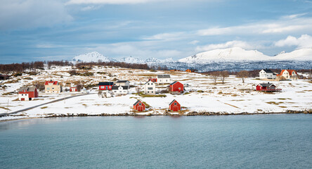 Idyllic view of traditional Norwegian houses in a snowy landscape on the island of Holdøya,...
