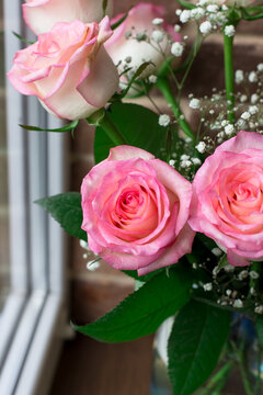 Bouquet of pink roses on the windowsill. Festive interior. Bouquet of flowers by the window