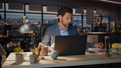 Serious businessman looking computer in night office closeup. Boss drinking tea